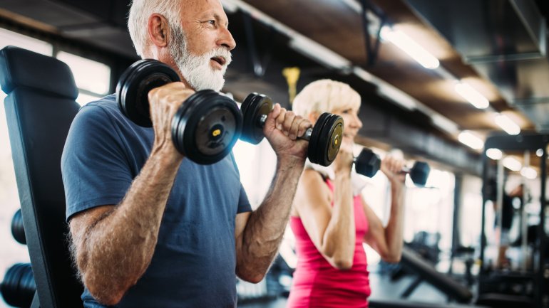 Ein älteres Paar macht Gewichtübungen im Fitnessstudio 