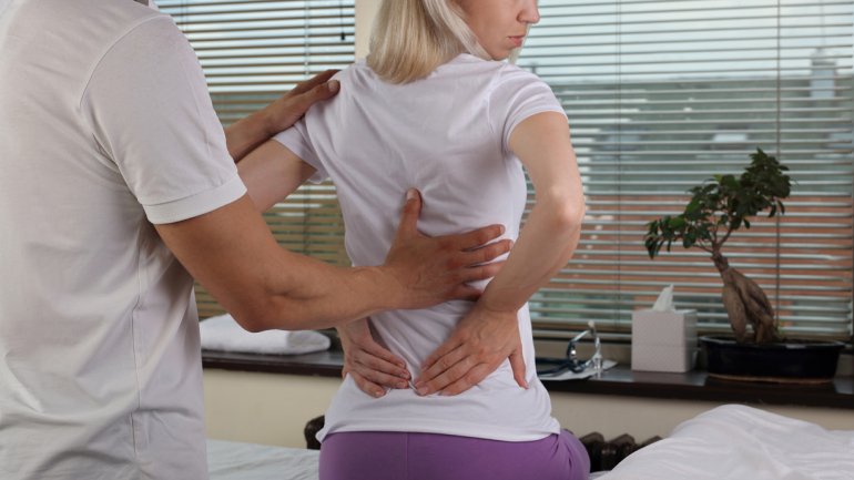 Frau wird in einem Schmerzzentrum von einem Arzt wegen Ihrer Rückenschmerzen behandelt