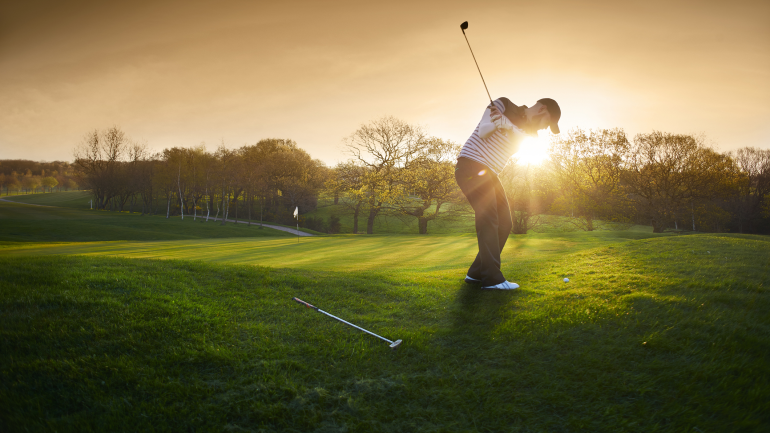 Golfspieler spielt auf dem Golfplatz bei Sonnenuntergang